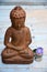 Brown Buddha statue with flowers and zen stones