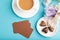 Brown business card with cup of cioffee, chocolate candies and iris flowers on blue pastel background. top view, copy space