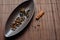 Brown canoe-shaped dish on bamboo mat with coffee beans, star anise, cloves and cinnamon