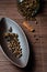 Brown canoe-shaped dish on bamboo mat with coffee beans, star anise, cloves and cinnamon