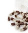 Brown capsules, pills poured out of a white bottle close-up on a white background.