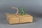 Brown cardboard box and a miniature dinosaur against a gray background. Small green figure of a predatory dinosaur standing on its