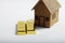 Brown cardboard home miniature and 999 gold bar ingot on a white isolated background