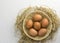 Brown chicken eggs in a basket on a separate straw on a white background