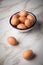 Brown chicken eggs in enamel bowl on marble background