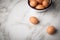 Brown chicken eggs in enamel bowl on marble background