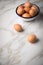 Brown chicken eggs in enamel bowl on marble background