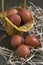 Brown chicken eggs in yellow basket and on the hay, green table, gray background. Easter preparations, Concept