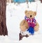 Brown children`s soft toy bear in a bright knitted scarf