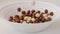 Brown choco cereal balls falling into a bowl, close up