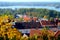 Brown city rooftops between golden forest in autumn in Czech Republic in Praha