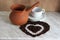brown clay Turk for cooking Arabic coffee, white Cup and saucer and roasted coffee beans in the shape of a heart
