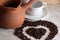 brown clay Turk for cooking Arabic Turkish coffee, white clean Cup and saucer and roasted coffee beans in the shape of a heart