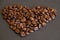Brown coffee beans heart shaped on a black slate plate