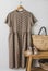 Brown cotton women\\\'s summer dress on a hanger on the wall, straw bag on a bench, retro shoes in the interior of the bedroom