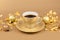 Brown Cup of coffee with saucer, gold christmas balls and pieces of gold paper firecracker on golden background. Aroma and good