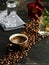 Brown cup with a strong freshly brewed espresso on a black background. Roasted coffee beans are located around the cup. Next to