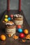 Brown Easter cakes decorated with chocolate, almond flakes and dried apricots among colored Easter eggs and tangerine zest on