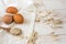 Brown eggs,dry oatmeal flakes on wooden spoon scattered over white linen cloth, wood background, healthy ingredients