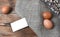 Brown eggs with empty paper card, willow branches, sackcloth on  wooden background.