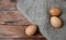 Brown eggs, sack fabric on wooden background. Easter minimalist or healthy eating concept.