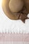 Brown floopy hat with ribbon and towel background. Top view. Sum