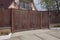 Brown gate of wooden planks and part of the fence on a rural street