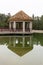 Brown gazebo on a green quiet lake in cloudy weather