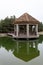 Brown gazebo on a green quiet lake in cloudy weather