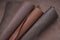 Brown genuine leather roll.real leather set. Leather in rolls on a blurred brown leather surface.Hobby and craft