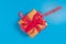 A brown gift box tied with a translucent red ribbon placed on blue background