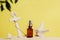 Brown glass bottle with cosmetic oil, anchor and starfish on a sandy beach. Summer skin care concept, yellow background