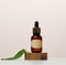 A brown glass bottle with a paper label and a pipette on a white table. Containers for cosmetics