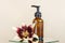 Brown glass bottle with pump of cosmetic products and lily flower on mirror, beige background. Natural Organic Spa
