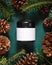 Brown glass jar near fir branches and pine cones on dark green top view. Brand packaging mockup
