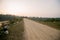 Brown gravel road In a rural area in Thailand There is a kilometer pole. In the back and with mountains During the time when the