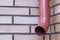 Brown gutter pipe against a brick wall background