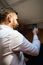 brown hair turkish guy elegant in white shirt sitting in his bed checking his smartphone reading messages