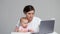 Brown-haired freelancer works on laptop with baby daughter