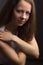 Brown-haired girl on a black background in white blouse. Contemptuous look. Hands at the collar