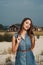 Brown haired rural lady standing on sand against ranch house