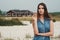 Brown haired rural lady standing on sand against ranch house