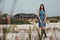 Brown haired rural lady standing on sand against ranch house