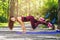 Brown-haired woman with long hair in a tracksuit doing exercises in the park using a suspension trainer