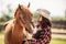 Brown horse leans towards a cowgirl on a ranch before horseriding