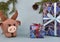 A brown knitted New Year\\\'s bull stands next to wrapped New Year\\\'s gifts. Behind him a cone hangs from a spruce branch.