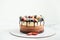 Brown layered cake Three chocolates decorated with bluberries, strawberries and chocolate drips on top