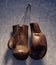 Brown leather boxing gloves hanging on grungy concrete wall