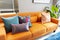 Brown leather sofa with blue and orange pillow in entertainment of luxury home.