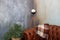 Brown leather sofa in dark loft interior. Cement grey wall with retro lamp. Living room with brown relax chair and floor lamp. Bas